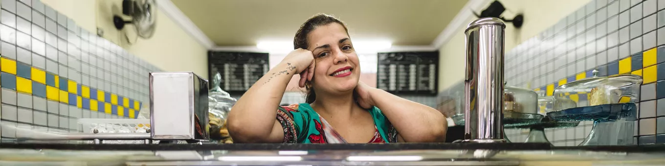 Foto mostra dona de lanchonete no seu estabelecimento