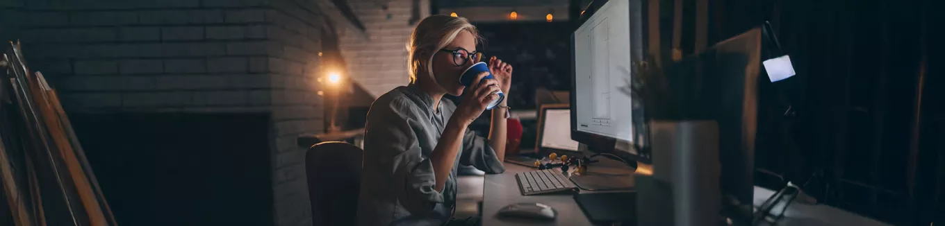 pessoa tomando chá enquanto trabalha à noite.