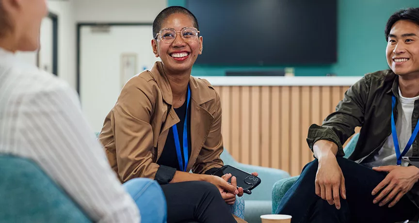 pessoas sorrindo em roda de conversa no trabalho.